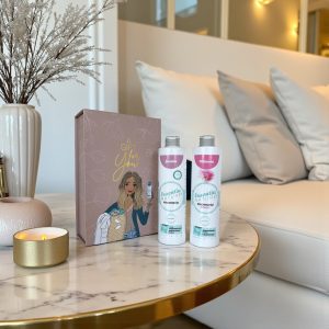 Cadeauset van Wasgeluk met Essentia Nature wasparfum Jasmin en Mimosa naast een roze giftbox met tekst “A gift for you” op een marmeren salontafel in een sfeervol, luxe interieur voor een langdurige, microplasticvrije geurbeleving.